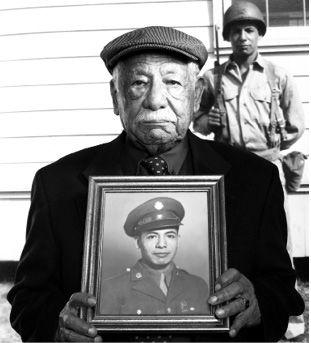 Photo of Mac Martinez holding a picture of himself in uniform