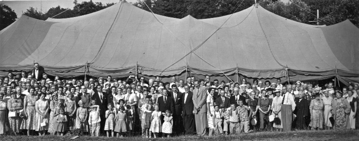 a large crowd in front of a big tent
