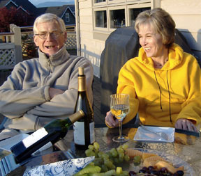 Gord and Chris Johnson at a table on their deck, with wine and grapes