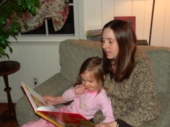 Jennifer reading a picture book to Violet on a sofa