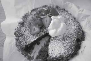 Chocolate mud cake dusted with powdered sugar, topped with strawberries and cream